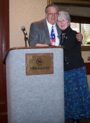 Linda Miller (right) hugs John Chrysler (left) after receiving a 2007 TMS Service Award for her exceptional contributions at TMS meetings.